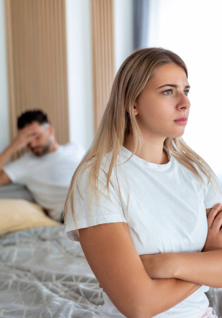 Upset couple sitting apart on a bed, get your ex back solution by astrologer Devraj Sharma