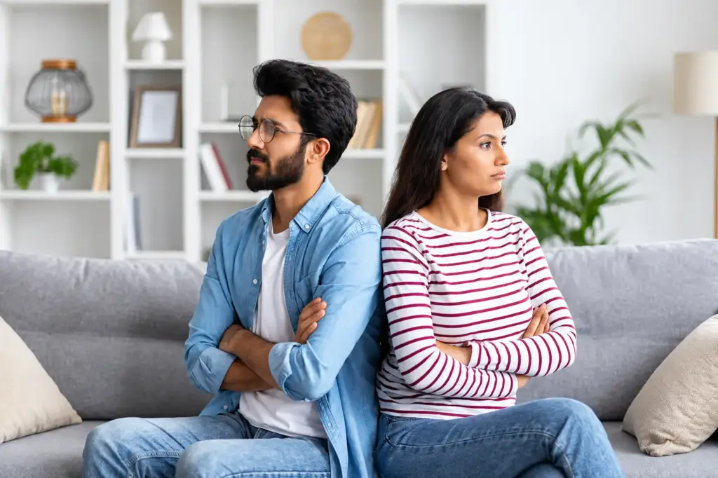 Indian couple sitting back to back with arms crossed, love problem solution by astrologer Devraj Sharma